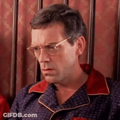 A Man Wearing Glasses And A Pajama Shirt Is Sitting In A Chair . GIF