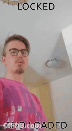 A Man Wearing Glasses And A Pink Shirt With The Words " Locked And Loaded " Below Him GIF