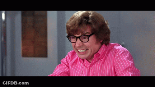 A Man Wearing Glasses And A Pink Striped Shirt Is Making A Funny Face GIF