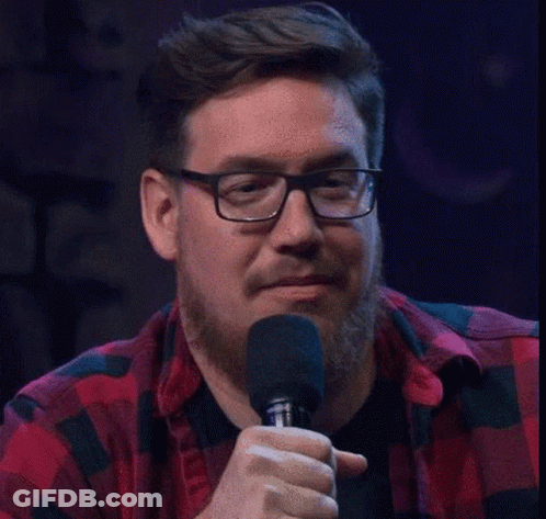 A Man Wearing Glasses And A Plaid Shirt Is Holding A Microphone . GIF
