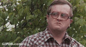 A Man Wearing Glasses And A Plaid Shirt Is Looking At Something . GIF
