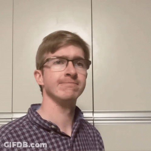 A Man Wearing Glasses And A Plaid Shirt Is Making A Face GIF
