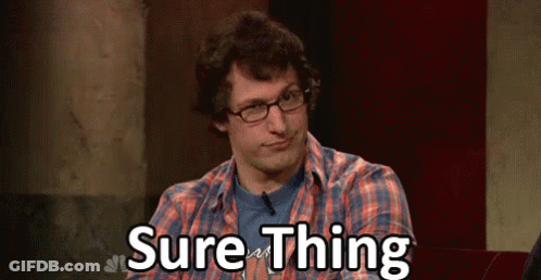 A Man Wearing Glasses And A Plaid Shirt Is Sitting In Front Of A Sign That Says Sure Thing . GIF