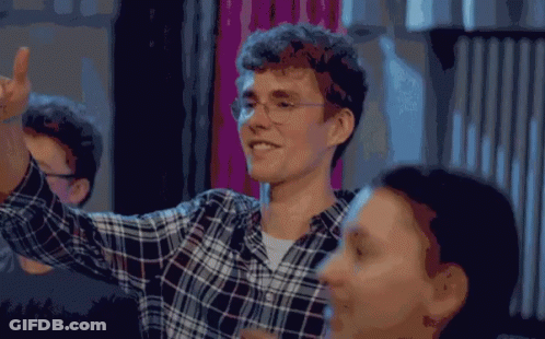 A Man Wearing Glasses And A Plaid Shirt Is Smiling And Giving A High Five GIF