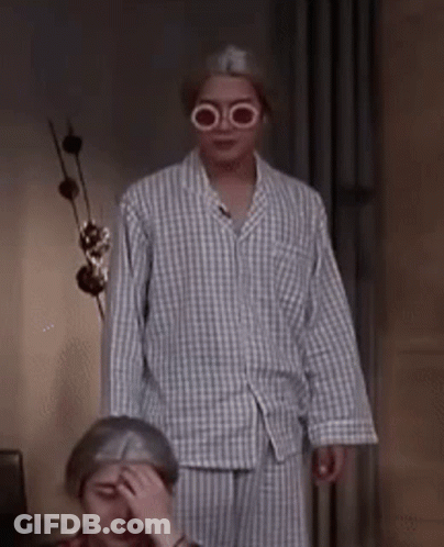 A Man Wearing Glasses And A Plaid Shirt Is Standing Next To A Woman Covering Her Face . GIF