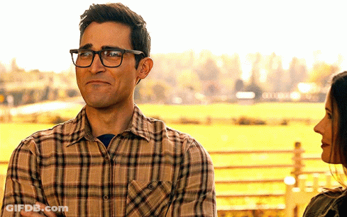 A Man Wearing Glasses And A Plaid Shirt Looks At A Woman In A Field GIF