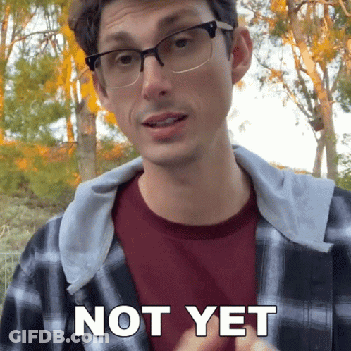 A Man Wearing Glasses And A Plaid Shirt Says " Not Yet " In Front Of Trees GIF