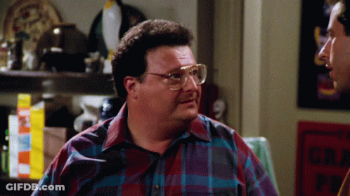 A Man Wearing Glasses And A Plaid Shirt Talks To Another Man In Front Of A Sign That Says No Parking GIF