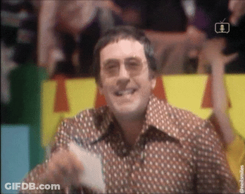 A Man Wearing Glasses And A Polka Dot Shirt Is Smiling GIF