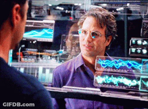 A Man Wearing Glasses And A Purple Shirt Is Looking At Another Man GIF