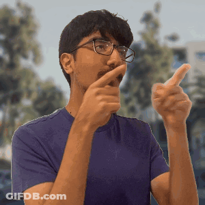 A Man Wearing Glasses And A Purple Shirt Is Pointing His Finger GIF
