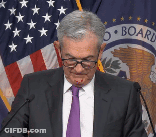 A Man Wearing Glasses And A Purple Tie Stands In Front Of A Microphone In Front Of A Flag That Says Board GIF