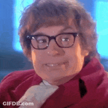 A Man Wearing Glasses And A Red Jacket Is Smiling GIF