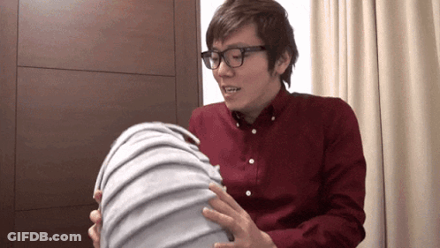 A Man Wearing Glasses And A Red Shirt Is Holding A Large Object GIF