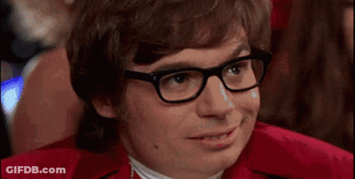 A Man Wearing Glasses And A Red Shirt Is Smiling And Looking At The Camera . GIF
