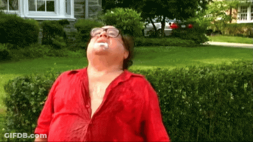 A Man Wearing Glasses And A Red Shirt Is Standing In Front Of A House With His Mouth Open .. GIF