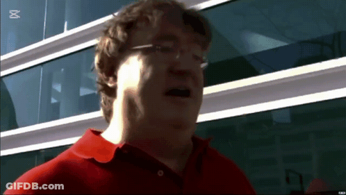 A Man Wearing Glasses And A Red Shirt Stands In Front Of A Building With The Letter M On The Bottom Right GIF