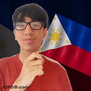 A Man Wearing Glasses And A Red Shirt Stands In Front Of A Flag GIF