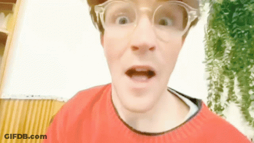 A Man Wearing Glasses And A Red Sweater Makes A Funny Face GIF