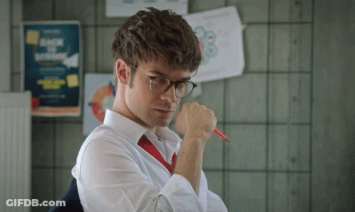A Man Wearing Glasses And A Red Tie Holds A Pen GIF