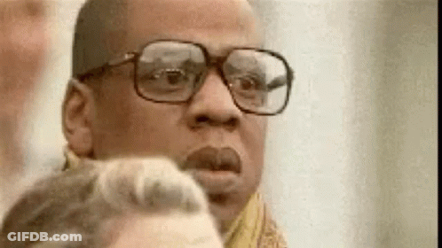 A Man Wearing Glasses And A Scarf Is Looking At A Woman . GIF