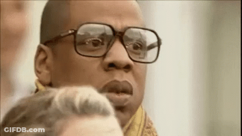A Man Wearing Glasses And A Scarf Is Looking At Something . GIF