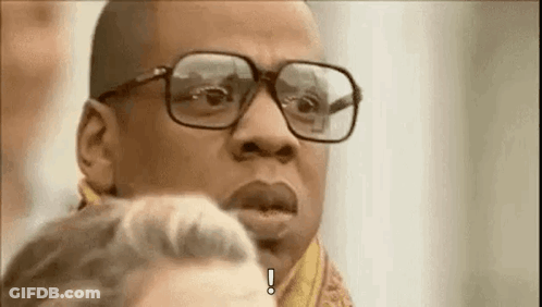 A Man Wearing Glasses And A Scarf Is Making A Funny Face . GIF