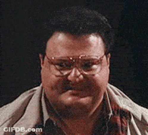 A Man Wearing Glasses And A Scarf Looks At The Camera GIF