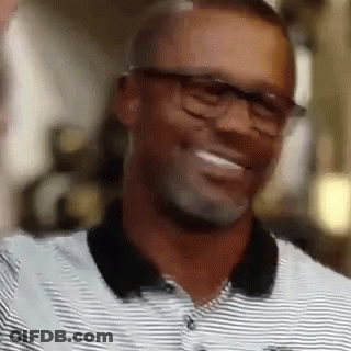 A Man Wearing Glasses And A Striped Shirt Is Laughing . GIF