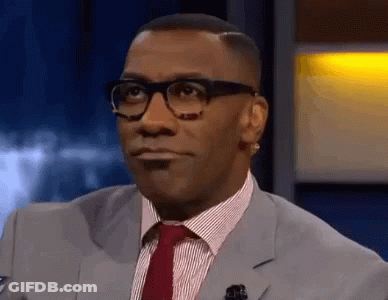 A Man Wearing Glasses And A Suit And Tie Is Looking At The Camera . GIF