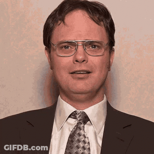 A Man Wearing Glasses And A Suit And Tie Is Smiling GIF