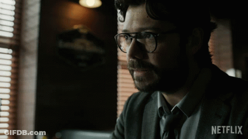 A Man Wearing Glasses And A Suit Has A Netflix Logo On His Sleeve GIF
