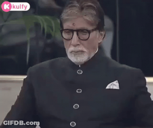 A Man Wearing Glasses And A Suit Is Clapping His Hands Together . GIF