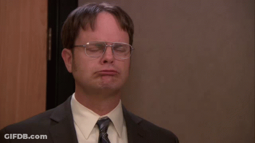 A Man Wearing Glasses And A Suit Is Making A Face GIF