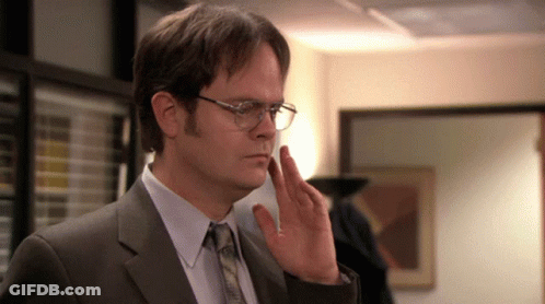 A Man Wearing Glasses And A Suit Is Making A Gesture With His Hand GIF