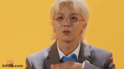 A Man Wearing Glasses And A Suit Is Making A Heart Shape With His Hands . GIF