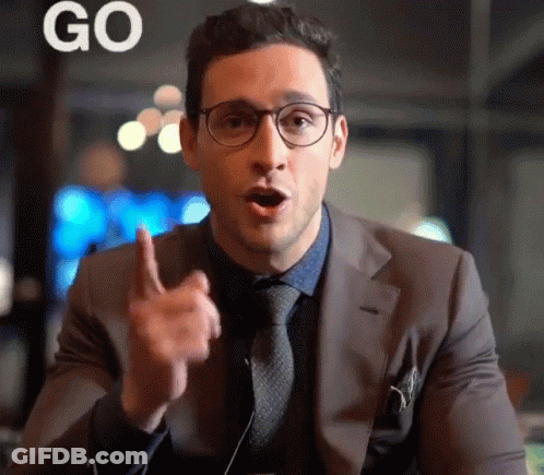 A Man Wearing Glasses And A Suit Is Pointing Up With The Word Go Behind Him GIF