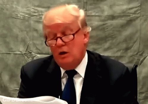 A Man Wearing Glasses And A Suit Is Reading A Paper GIF