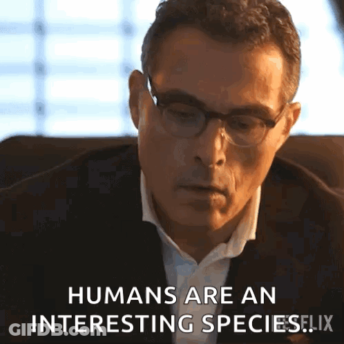 A Man Wearing Glasses And A Suit Is Sitting In A Chair And Says Humans Are An Interesting Species . GIF