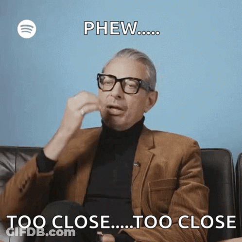 A Man Wearing Glasses And A Suit Is Sitting On A Couch And Says Phew Too Close Too Close . GIF