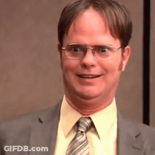 A Man Wearing Glasses And A Suit Is Smiling And Making A Funny Face . GIF