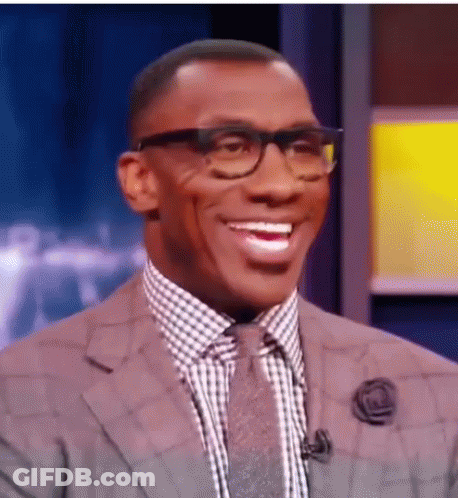 A Man Wearing Glasses And A Suit Is Smiling . GIF