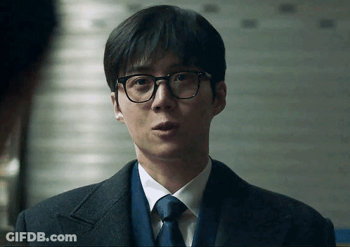 A Man Wearing Glasses And A Suit Looks At The Camera GIF