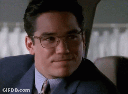 A Man Wearing Glasses And A Suit Looks At The Camera GIF