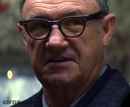 A Man Wearing Glasses And A Suit Looks At The Camera GIF