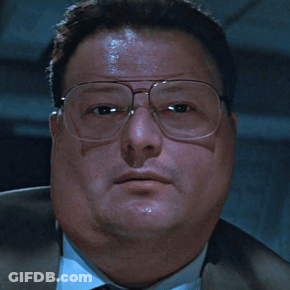 A Man Wearing Glasses And A Suit Looks At The Camera With A Serious Look On His Face GIF