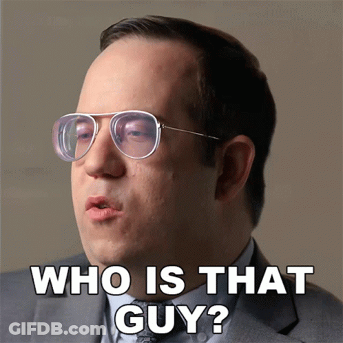A Man Wearing Glasses And A Suit Says " Who Is That Guy " GIF
