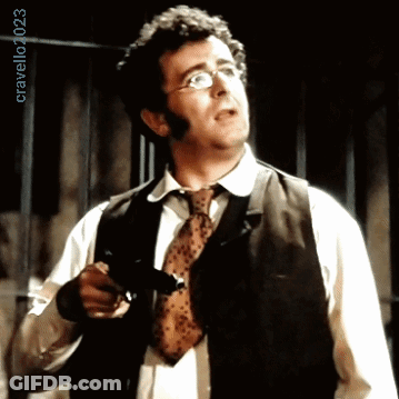 A Man Wearing Glasses And A Tie Is Holding A Gun In Front Of A Sign That Says Cravello40253 GIF