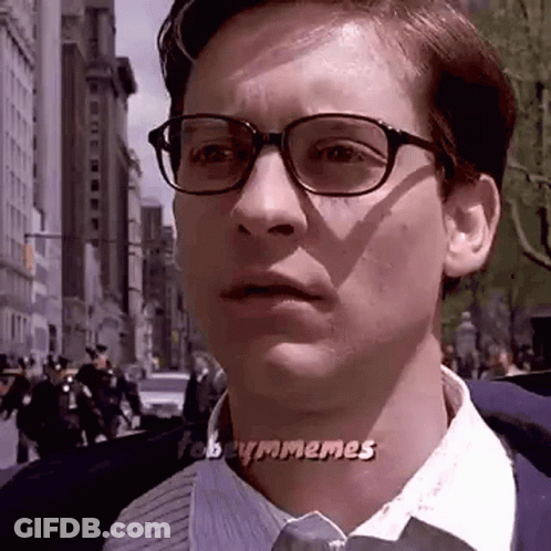 A Man Wearing Glasses And A Tie Is Looking At The Camera . GIF