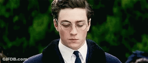 A Man Wearing Glasses And A Tie Is Looking Down . GIF